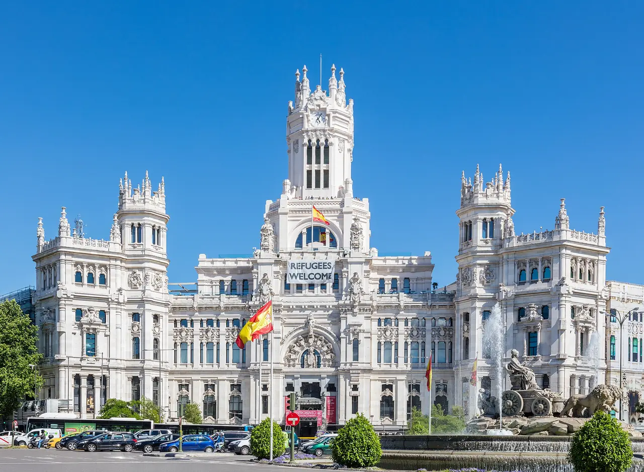 อาคารบริเวณ Plaza de Cibeles ในมาดริดพร้อมน้ำพุ ภาพถ่ายจาก Wikimedia Commons ผู้ถ่าย Diego Delso สัญญา CC BY-SA 4.0 ไฟล์ในคอมมอนส์ใช้ชื่อ Palacio de Comunicaciones