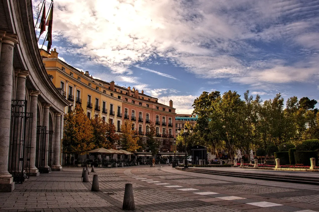 Plaza de Oriente ในมาดริด ระเบียงอาคารและต้นไม้ใกล้พระราชวัง ภาพถ่ายจาก Wikimedia Commons ผู้ถ่าย Felipe Gabaldon สัญญา CC BY 2.0 ตำแหน่งที่ถ่ายยังไม่ยืนยัน