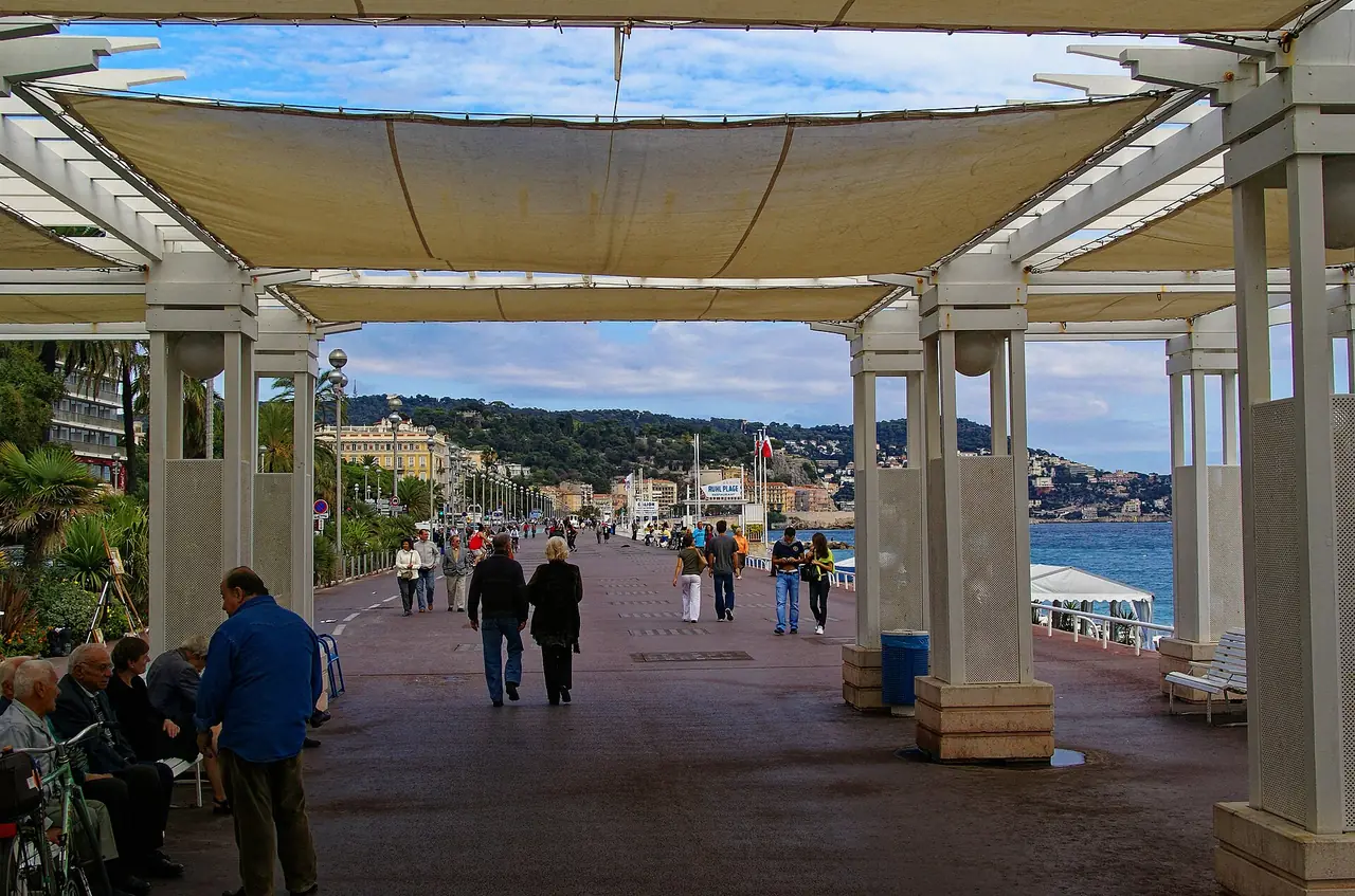 ทางเดินใต้ซุ้มเสาบน Promenade des Anglais ในนีซ มองไปทางทะเลและแนวเนินทางตะวันออก ภาพจาก Wikimedia Commons ผู้ถ่าย Txllxt TxllxT สัญญา CC BY-SA 4.0