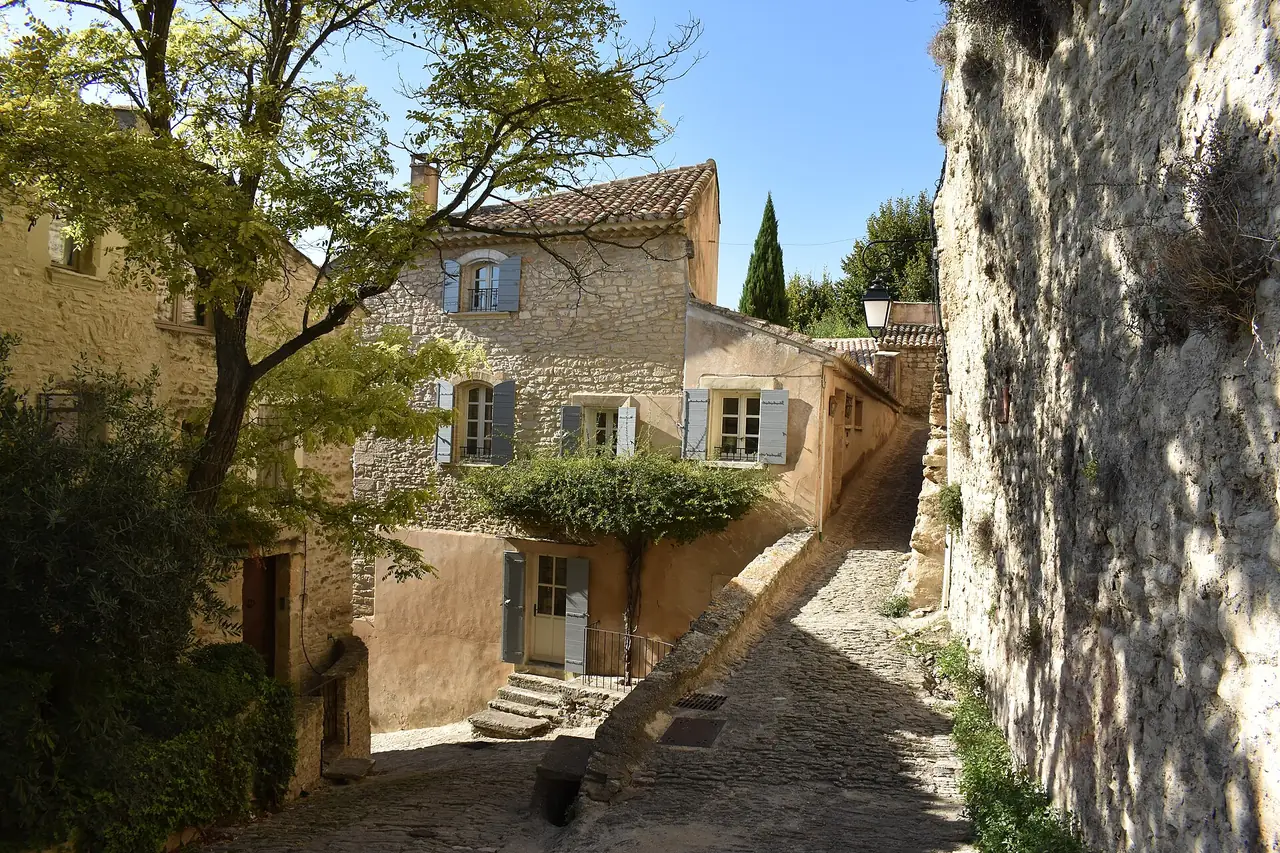 ซอยหินแคบในหมู่บ้าน Gordes มีบ้านหินและต้นไม้ ภาพจาก Wikimedia Commons ผู้ถ่าย Michael F. H. Barth สัญญา CC BY-SA 4.0