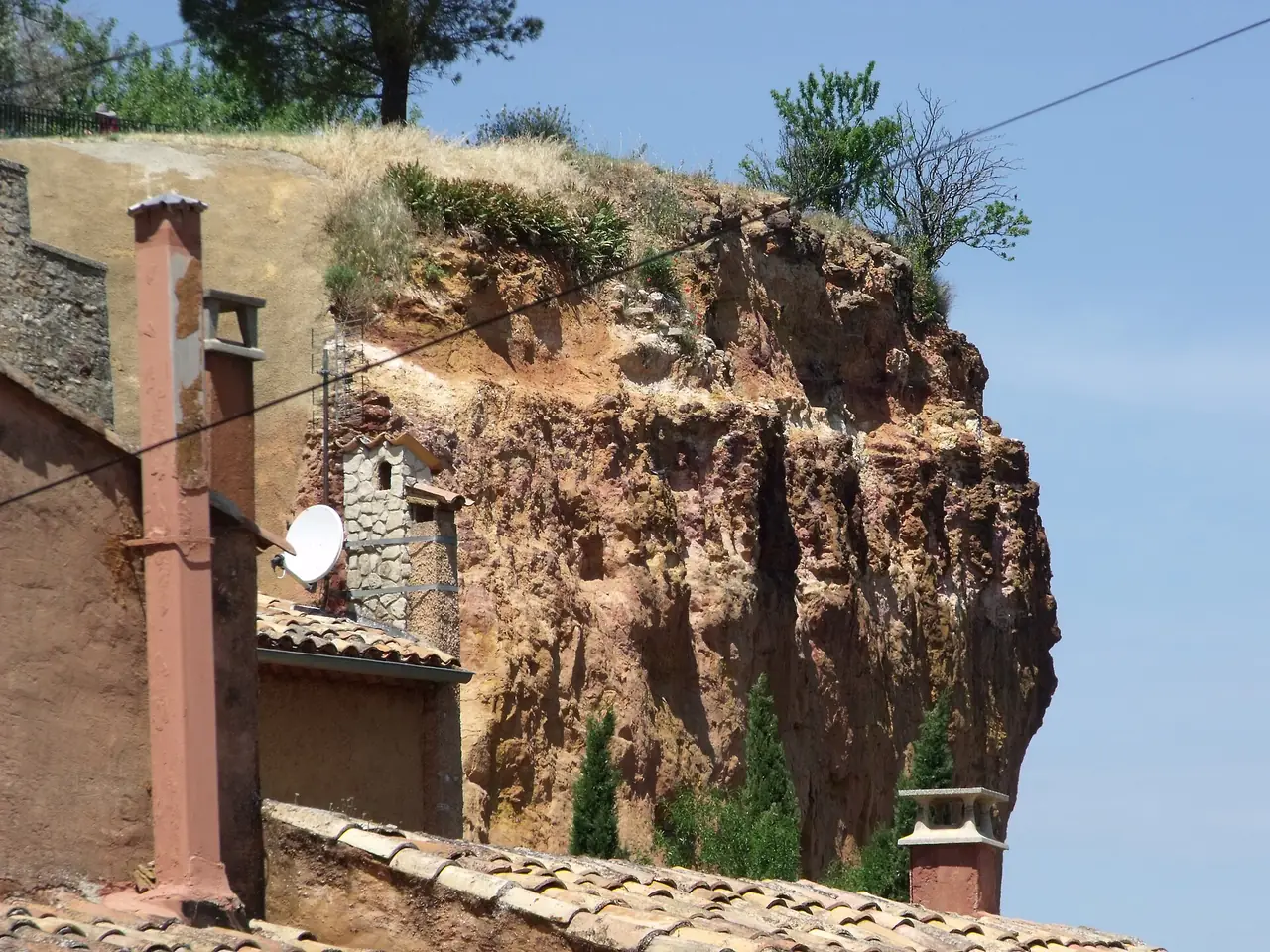 หน้าผาดินเหลืองส้มและบ้านหลังคากระเบื้องในหมู่บ้าน Roussillon ภาพประกอบหมู่บ้านใกล้เคียงใน Luberon ภาพจาก Wikimedia Commons ผู้ถ่าย Elliott Brown สัญญา CC BY 2.0