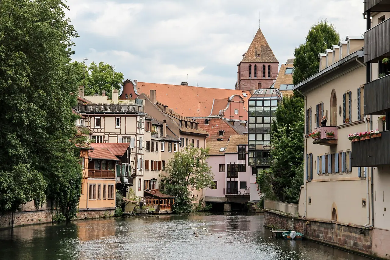 ย่าน Petite France ในสตราสบูร์ก บ้านไม้ครึ่งปูนริมคลองและยอดโบสถ์ ภาพถ่ายปี 2554 ภาพจาก Wikimedia Commons ผู้ถ่าย Dietmar Rabich สัญญา CC BY-SA 4.0