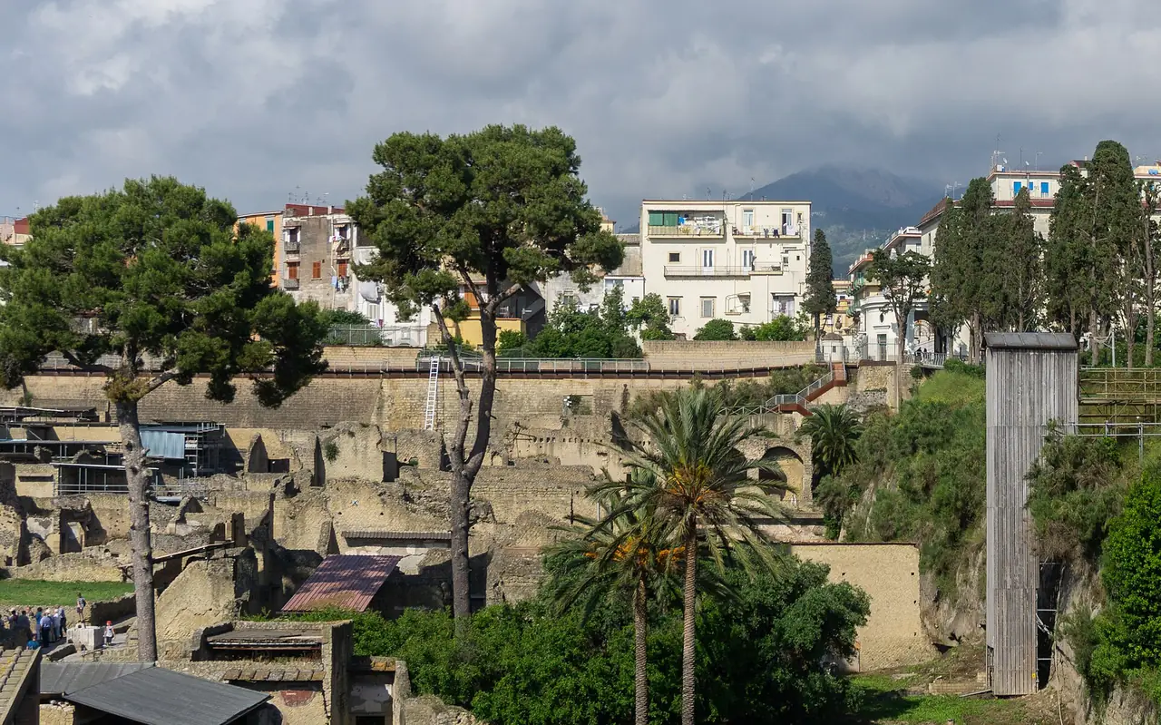 ซากเมือง Herculaneum ติดกับเมือง Ercolano สมัยใหม่ และภูเขาเวซูเวียสไกลๆ ภาพจาก Wikimedia Commons ผู้ถ่าย Sumit Surai สัญญา CC BY-SA 4.0