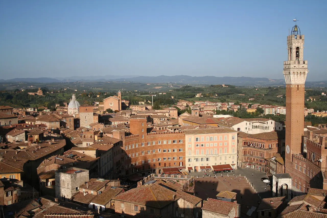 ภาพมุมสูงของเมืองเก่าซีเอนา มีหอ Torre del Mangia ทางขวา ภาพจาก Wikimedia Commons ผู้ถ่าย Massimo Catarinella สัญญา CC BY-SA 3.0