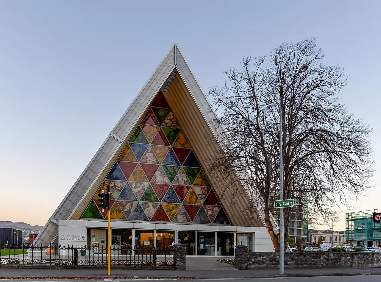 ด้านหน้า Cardboard Cathedral ในไครสต์เชิร์ช มีกระจกสีสามเหลี่ยมและโครงรูปตัวเอ ภาพจาก Wikimedia Commons ผู้ถ่าย Michal Klajban สัญญา CC BY-SA 4.0