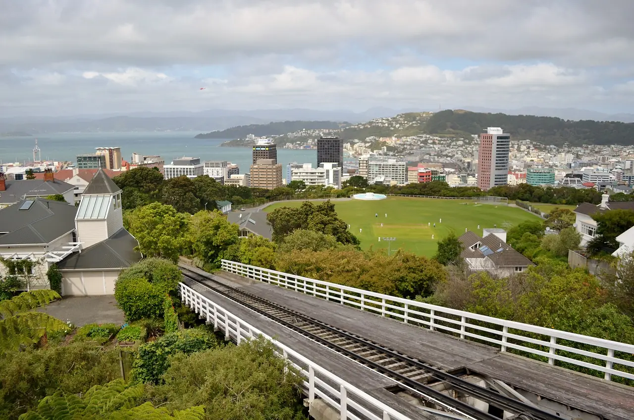 รางของ Wellington Cable Car และสนามคริกเก็ต Kelburn Park กับเมืองเวลลิงตันด้านหลัง ภาพจาก Wikimedia Commons ผู้ถ่าย Bahnfrend สัญญา CC BY-SA 4.0 ถ่ายปี 2556