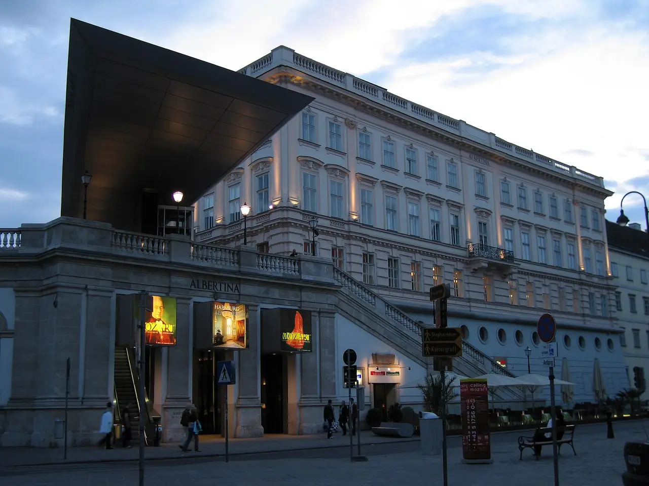 ด้านหน้า Albertina ยามเย็น มองเห็นหลังคาแผ่นโลหะยื่นที่ทางเข้าและบันไดทางขึ้นป้อม ภาพจาก Wikimedia Commons ผู้ถ่าย Florian Prischl สัญญา CC BY-SA 3.0 ปีถ่ายไม่ระบุในที่เราตรวจ