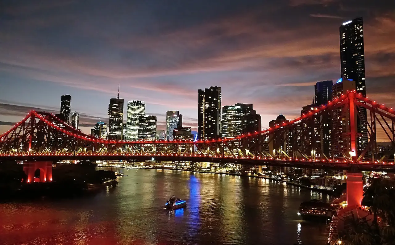 สะพาน Story Bridge เปิดไฟสีแดงยามค่ำ มีตึกกลางเมืองเป็นฉากหลัง บริสเบน ภาพจาก Wikimedia Commons ผู้ถ่าย King Eliot สัญญา CC BY 4.0