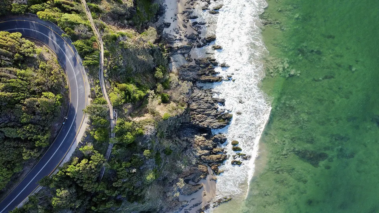 ภาพถ่ายมุมสูงของถนนและทางเดินชายฝั่งหินบน Cape Byron ที่ติดทะเลสีเขียว ภาพจาก Wikimedia Commons ผู้ถ่าย Cinelab Productions สัญญา CC BY-SA 4.0