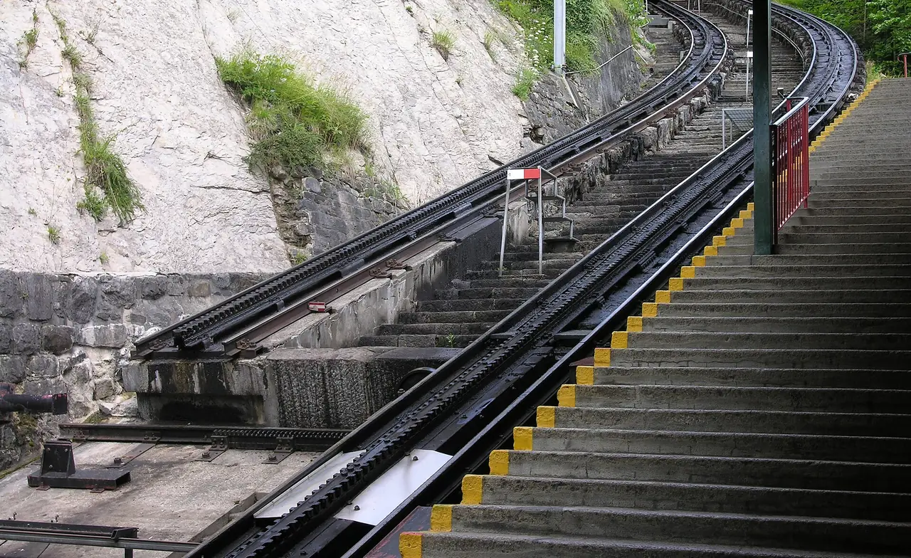 รางฟันเฟืองและบันไดที่สถานี Alpnachstad ตามชื่อไฟล์คือแท่นเลื่อนรถ (transfer table) ของ Pilatusbahn ภาพจาก Wikimedia Commons ผู้ถ่าย Audriusa สัญญา CC BY-SA 3.0 ไม่ทราบปีที่ถ่าย