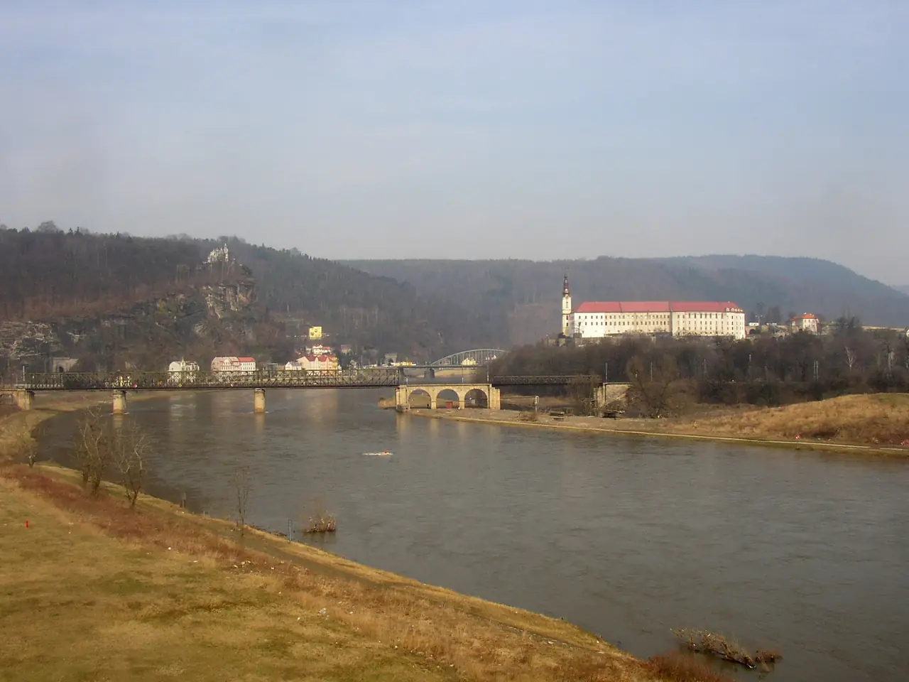 ปราสาท Děčín ริมแม่น้ำเอลเบอ เมืองประตูของอุทยานที่รถไฟจากปรากมาถึง ภาพจาก Wikimedia Commons ผู้ถ่าย Miaow Miaow สัญญา CC BY-SA 3.0 ไม่ทราบปีที่ถ่าย