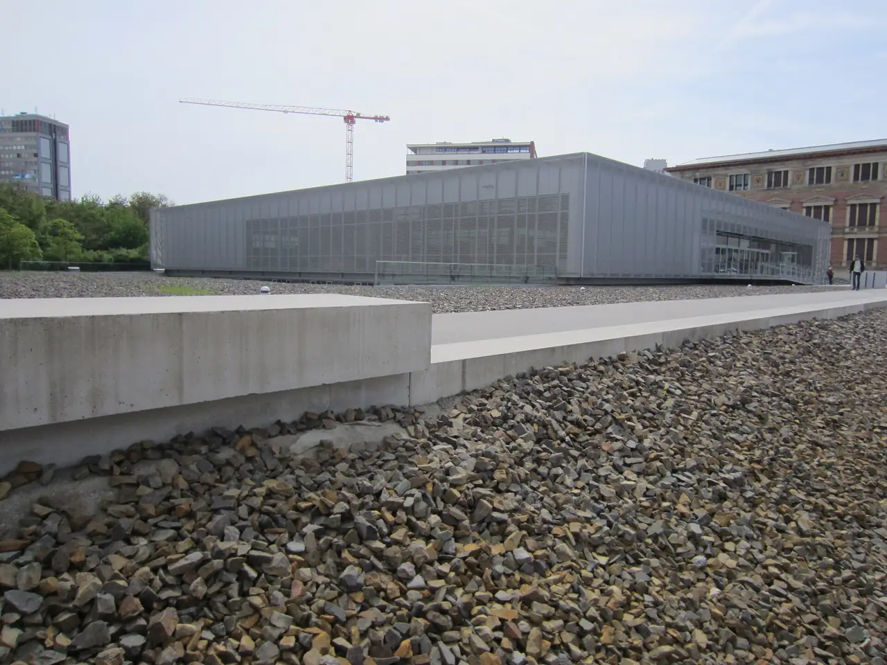 อาคารนิทรรศการของ Topography of Terror เห็นพื้นกรวดของลานกลางแจ้งด้านหน้า ภาพจาก Wikimedia Commons ผู้ถ่าย Another Believer สัญญา CC BY-SA 4.0 ถ่ายปี 2558