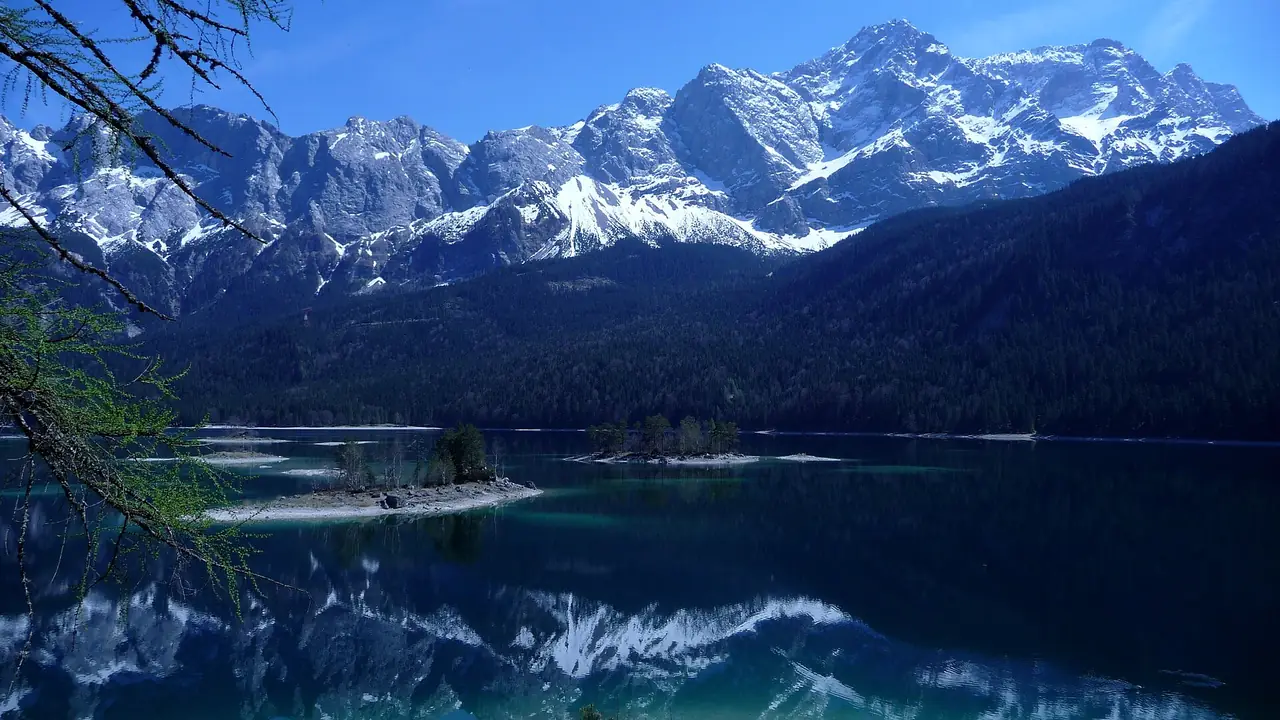 ทะเลสาบ Eibsee ช่วงที่ยอดเขาเริ่มมีหิมะ เห็นเกาะเล็กและเงาสะท้อนบนน้ำ ภาพจาก Wikimedia Commons ผู้ถ่าย GraceKelly สัญญา CC BY-SA 3.0 ปีที่ถ่ายตามชื่อไฟล์คือ 2553