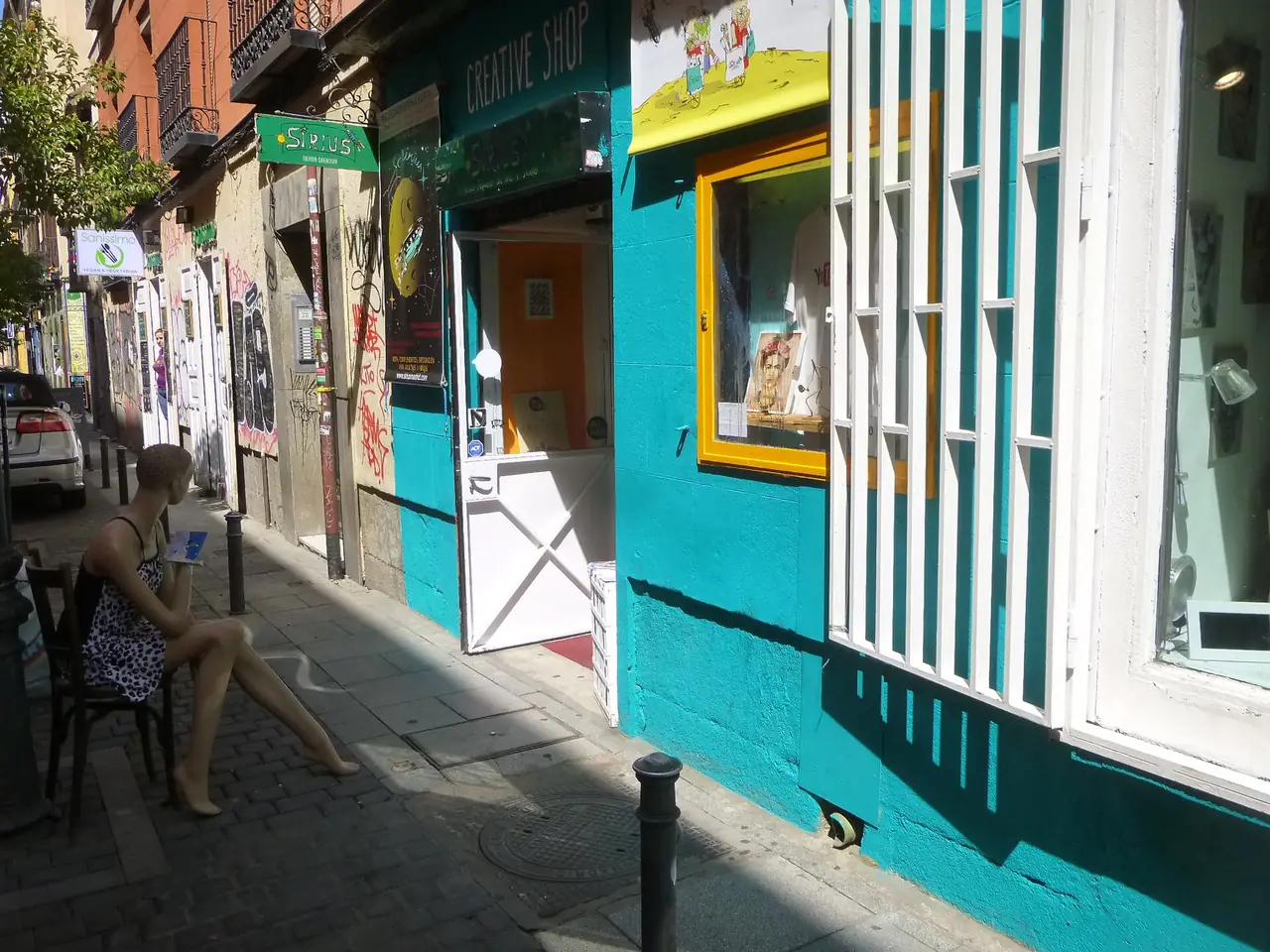 ถนนเล็กในย่าน Malasaña ที่มีร้านค้าเรียงติดกัน ภาพถ่ายจาก Wikimedia Commons ผู้ถ่าย Zarateman สัญญา CC0 ไม่ใช่ภาพจากโรงแรมและไม่ระบุปีที่ถ่าย