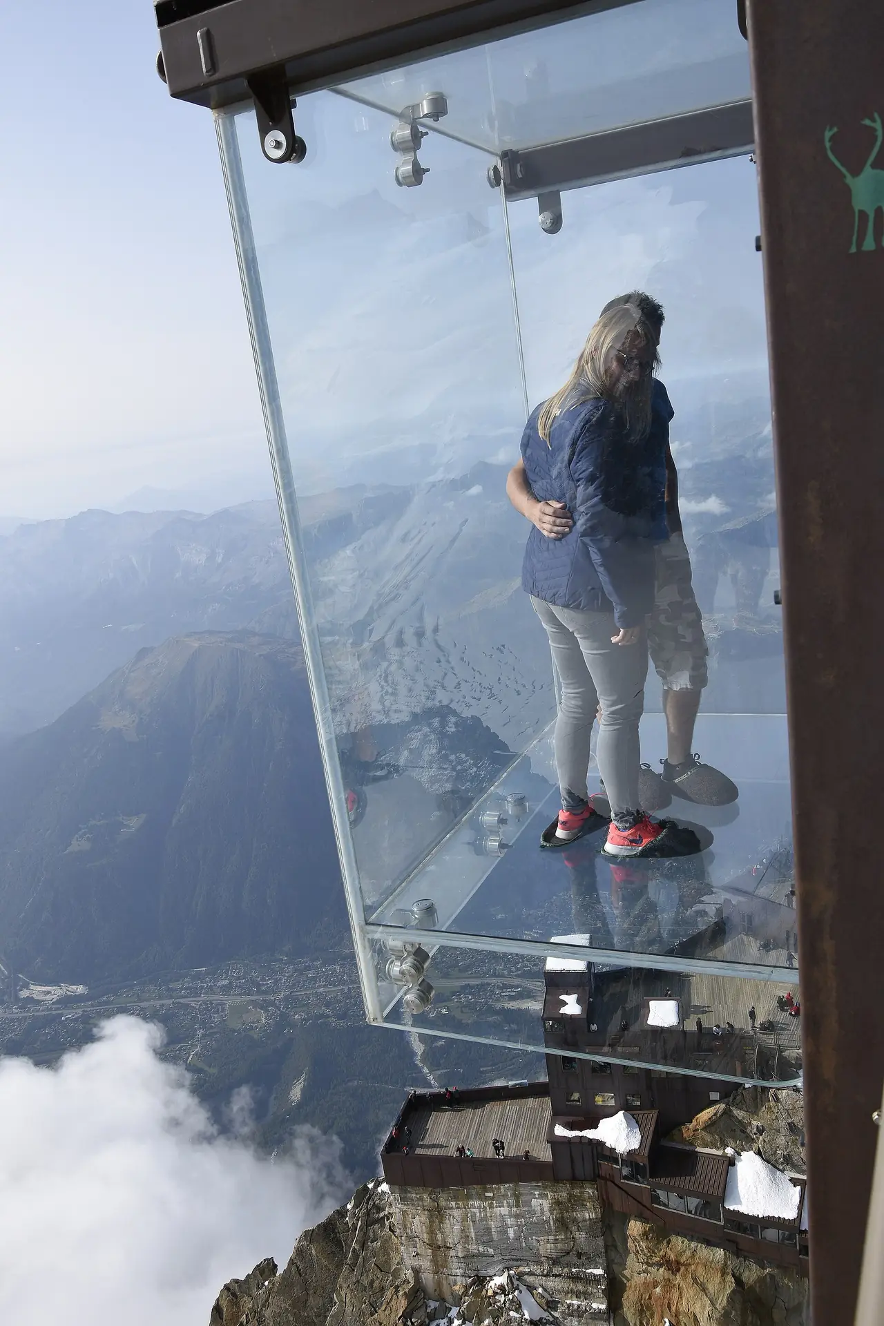 กล่องกระจก Pas dans le Vide ที่ยอด Aiguille du Midi มีผู้ชมสองคนยืนอยู่ ภาพถ่ายปี 2017 จาก Wikimedia Commons ผู้ถ่าย Paul Hermans สัญญา CC BY-SA 4.0