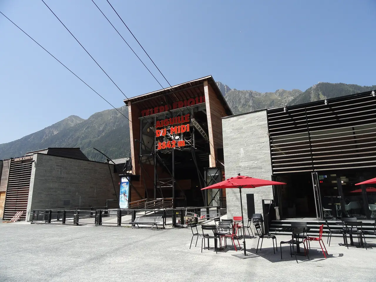 สถานีกระเช้า Aiguille du Midi ที่ Chamonix มีร่มสีแดงและร้านอาหารด้านหน้า ภาพจาก Wikimedia Commons ผู้ถ่าย Kristoferb สัญญา CC BY-SA 3.0