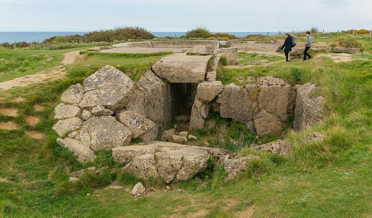 ซากบังเกอร์เยอรมันที่ Pointe du Hoc มีนักท่องเที่ยวเดินอยู่บนสนามหญ้าเหนือทะเล ภาพจาก Wikimedia Commons ผู้ถ่าย Jebulon สัญญา CC0