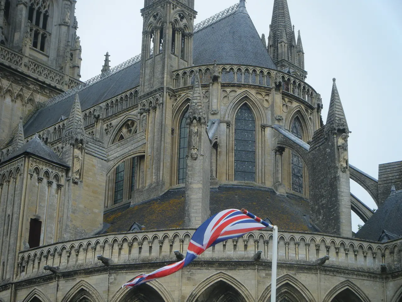 ส่วนท้ายอาสนวิหาร Bayeux มองจากด้านนอก มีธงชาติอังกฤษประดับที่ราวบันได ภาพจาก Wikimedia Commons ผู้ถ่าย MagicRubberDuck สัญญา CC BY-SA 4.0