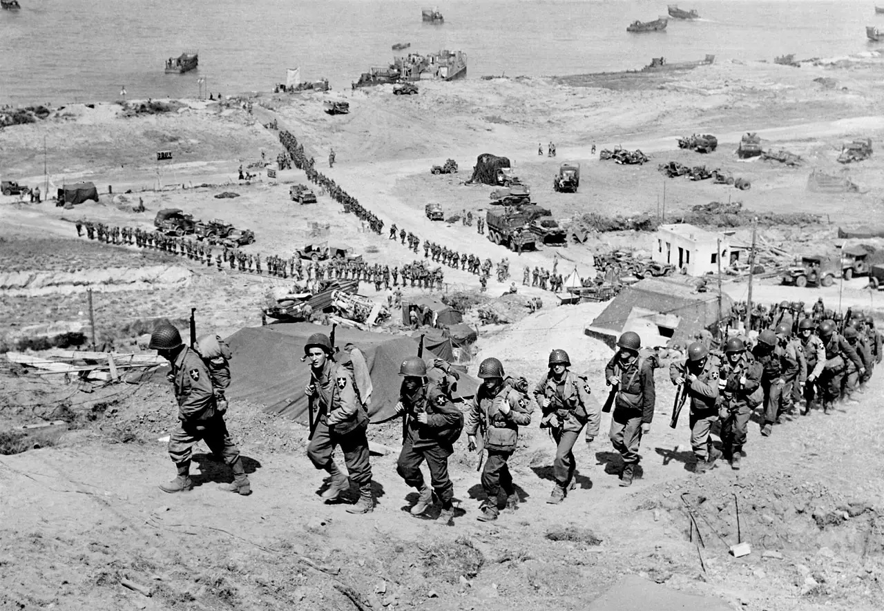 ทหารสหรัฐเดินขึ้นจากหาด Omaha ในเขต Easy Red ภาพขาวดำเมื่อ 7 มิถุนายน 1944 ภาพประวัติศาสตร์จาก US Army Signal Corps สถานะ Public domain ผ่าน Wikimedia Commons