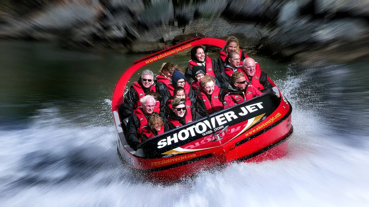 เรือ Shotover Jet สีแดงกับผู้โดยสารสวมเสื้อชูชีพ ภาพจาก Wikimedia Commons ผู้ถ่าย Bernard Spragg สัญญา CC0 ภาพจากเว็บภาพของผู้ถ่ายท่านนี้ ไม่ระบุปี