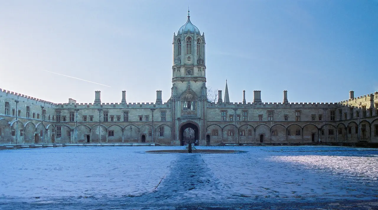 ลาน Tom Quad ของ Christ Church และหอ Tom Tower ในวันที่มีหิมะ ภาพจาก Wikimedia Commons ผู้ถ่าย Toby Ord สัญญา CC BY-SA 2.5 ถ่ายปี 2004 เป็นภาพเก่า