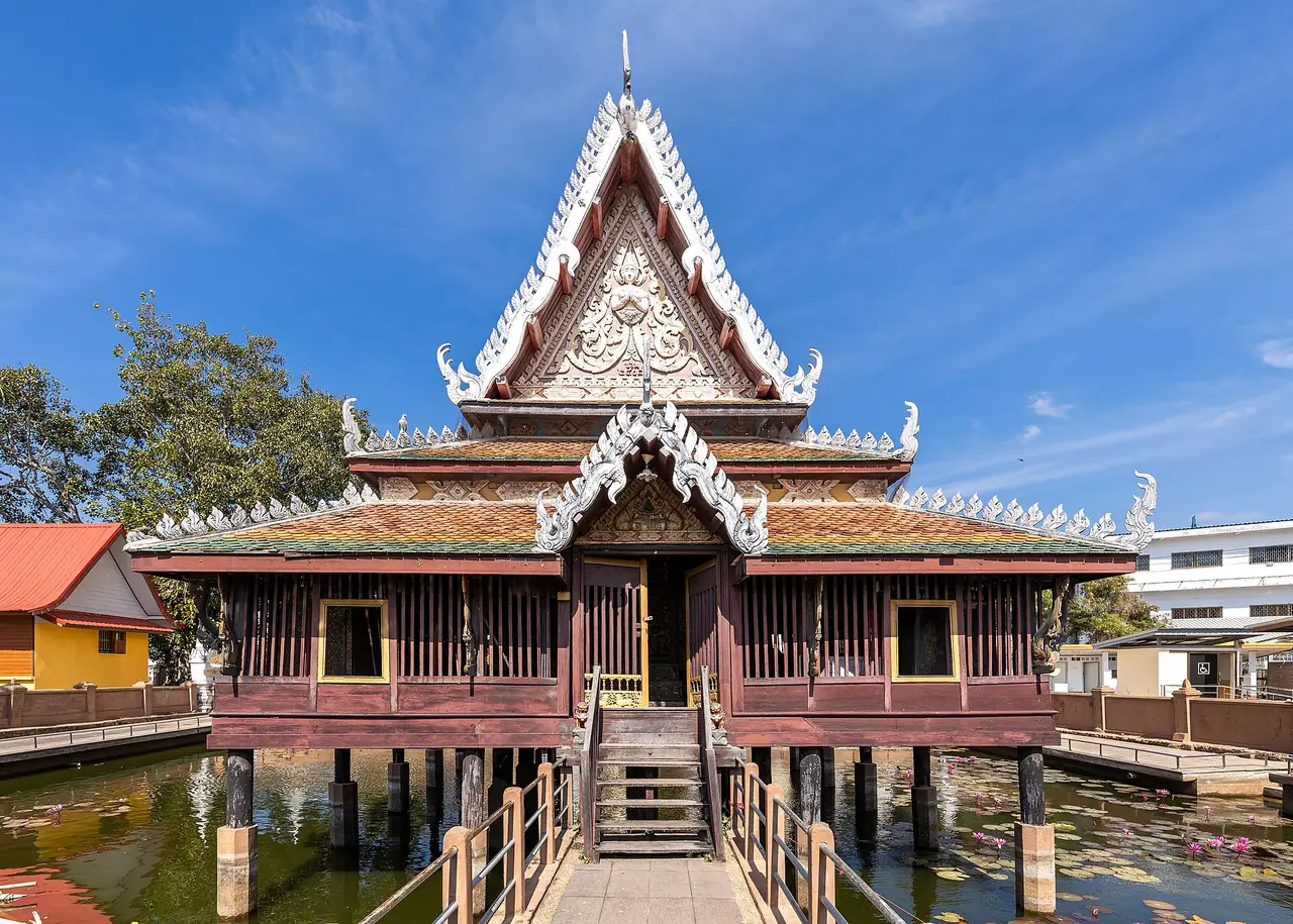 A wooden scripture-library-style hall on stilts in a pond at Wat Maha That, Yasothon