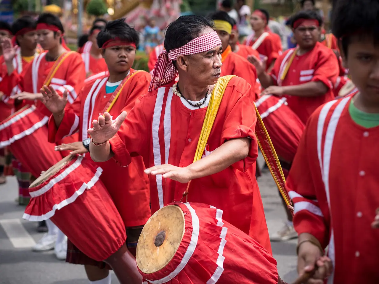 ผู้ร่วมขบวนตีกลองในชุดสีแดงที่งานบุญบั้งไฟยโสธร ภาพของ Takeaway จาก Wikimedia Commons ใบอนุญาต CC BY-SA 3.0 ชื่อไฟล์ระบุปี 2013 เป็นภาพงานปีเก่า